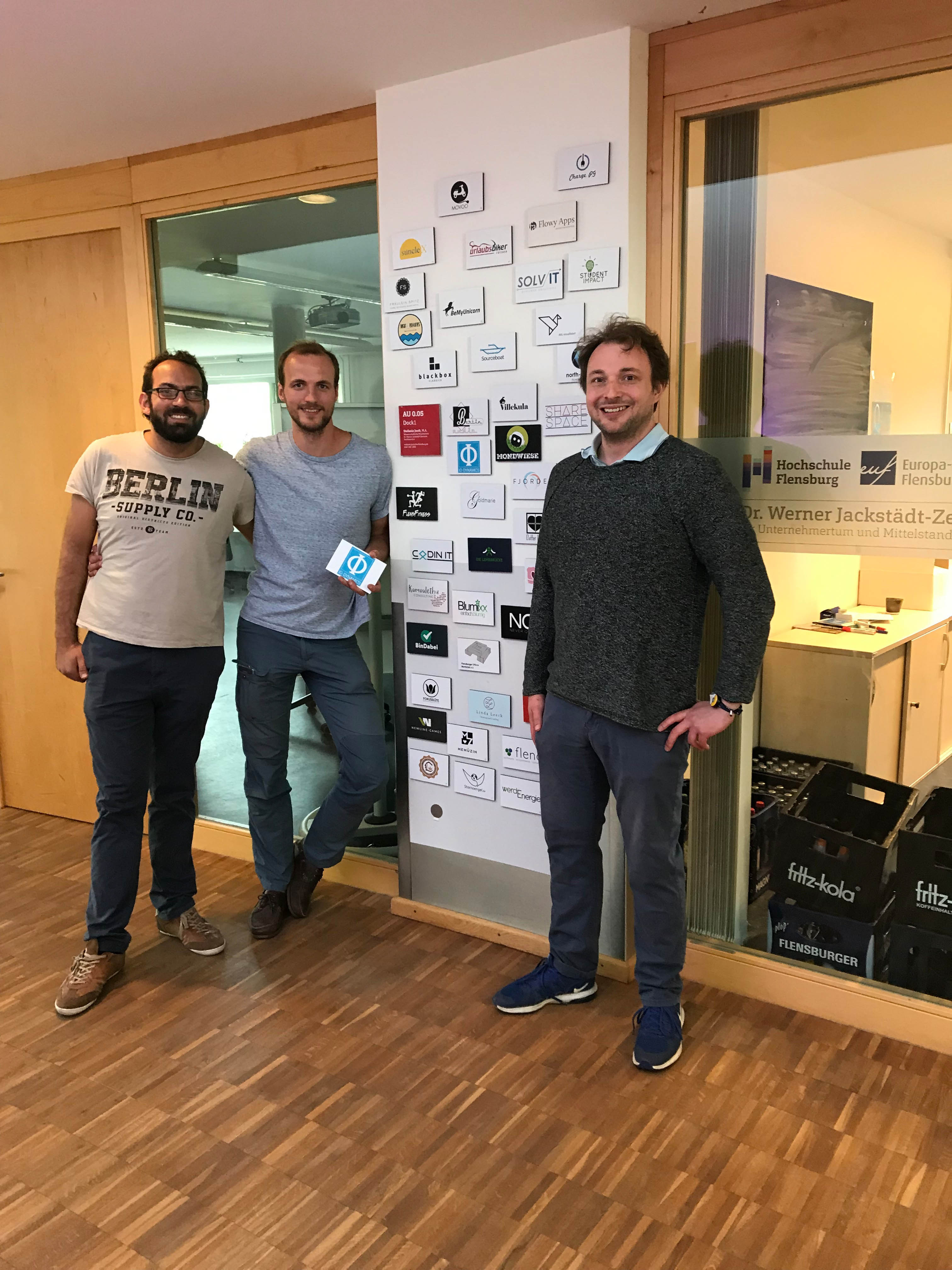 The founders of IO-Dynamics in front of the wall of fame