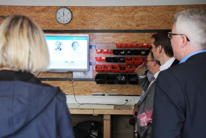 Group of people looking at a screen hanging on the wall.